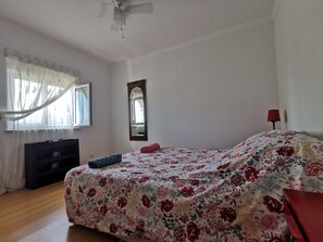 Cozy retreat with a large bed, ceiling fan, and mirror.