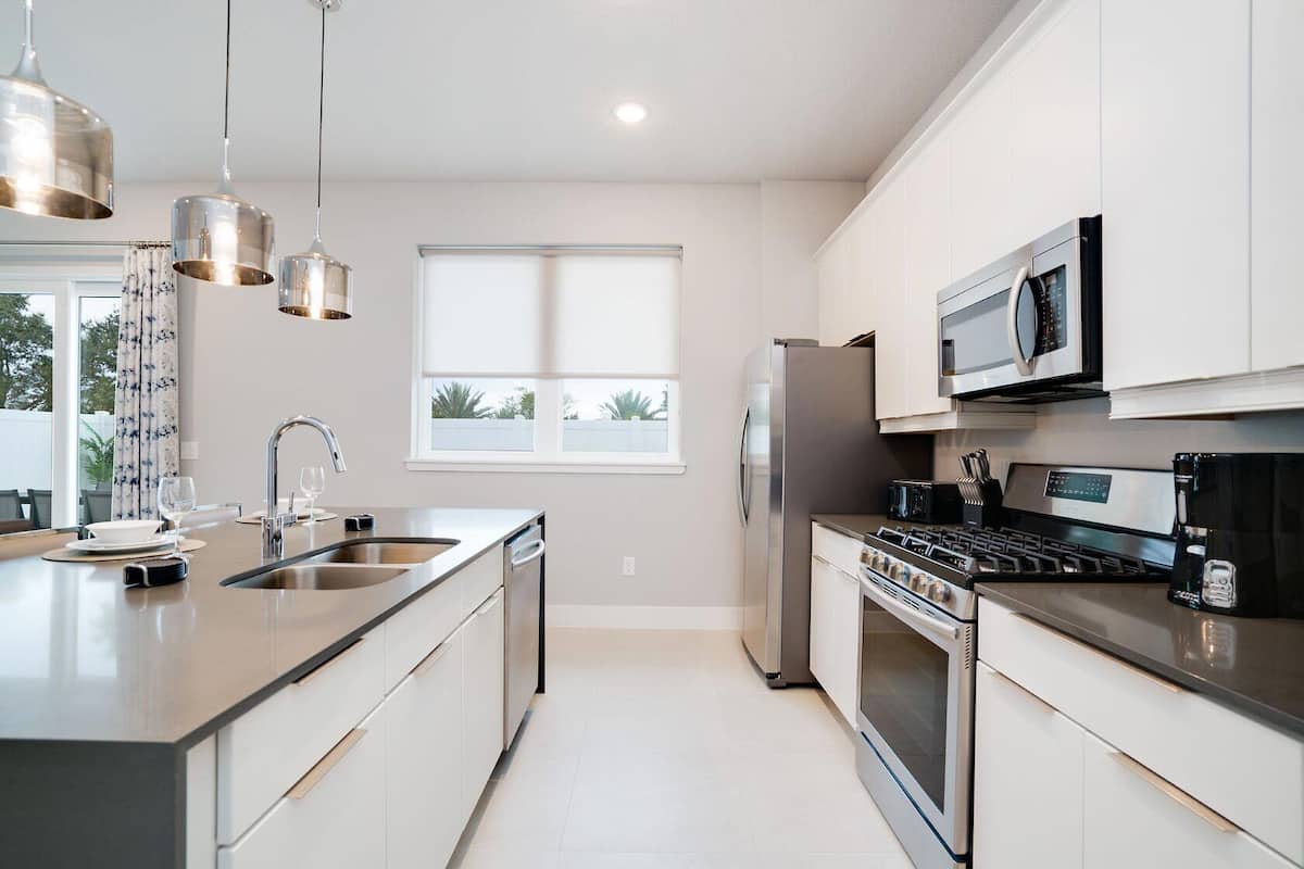 A modern kitchen with stainless steel appliances, a large island with a sink, and pendant lighting.