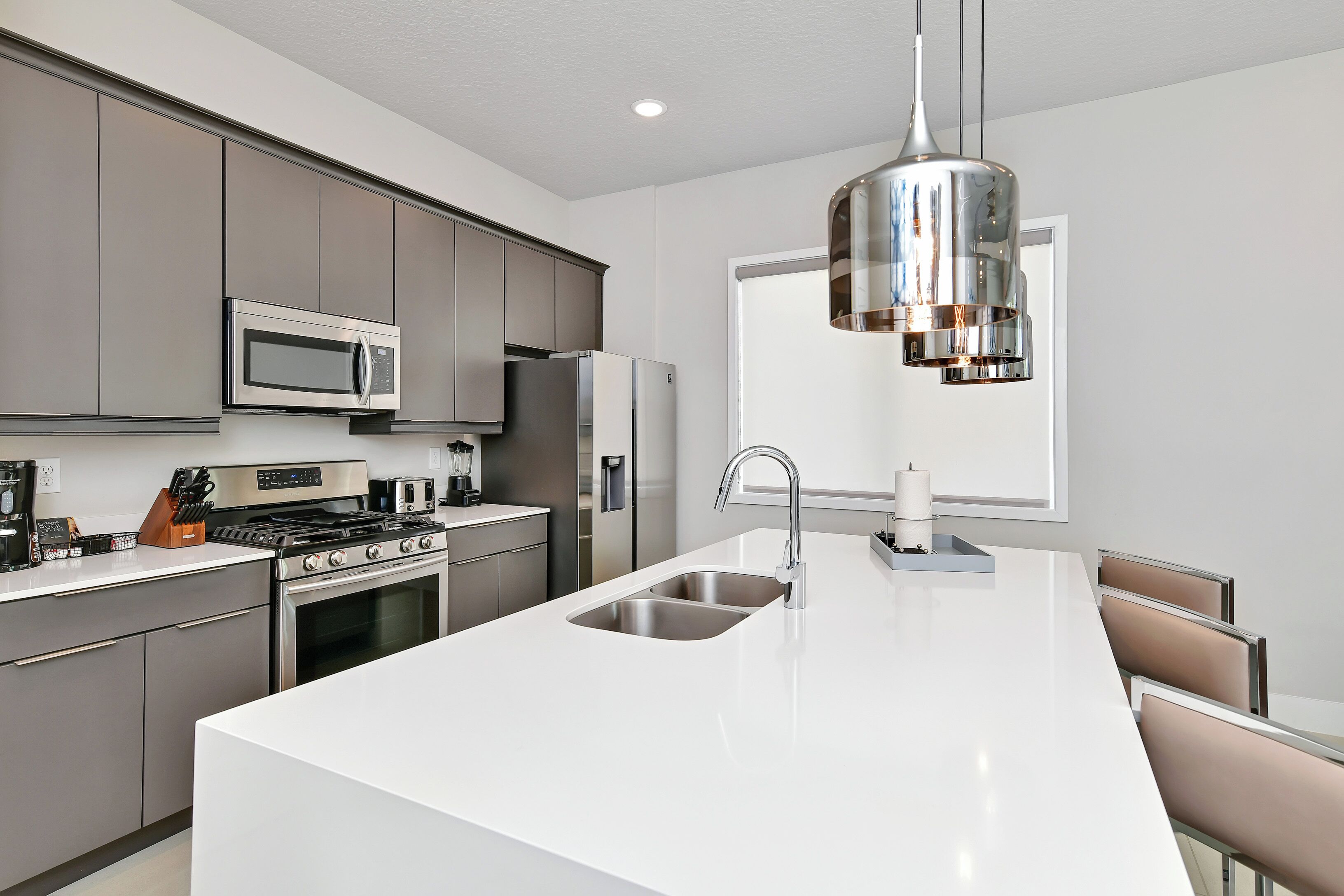 A modern kitchen with stainless steel appliances, a large island with a sink, and a pendant light.