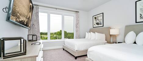 A hotel room with two beds, a ceiling fan, a large window, and a TV mounted on the wall.