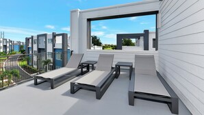 A rooftop terrace with modern outdoor furniture, a view of the city, and a clear sky. - Spectrum Resort Villas Orlando and Waterparks (Kissimmee)