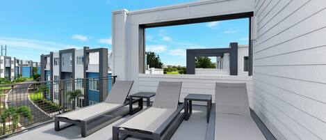 A rooftop terrace with modern outdoor furniture, a view of the city, and a clear sky.