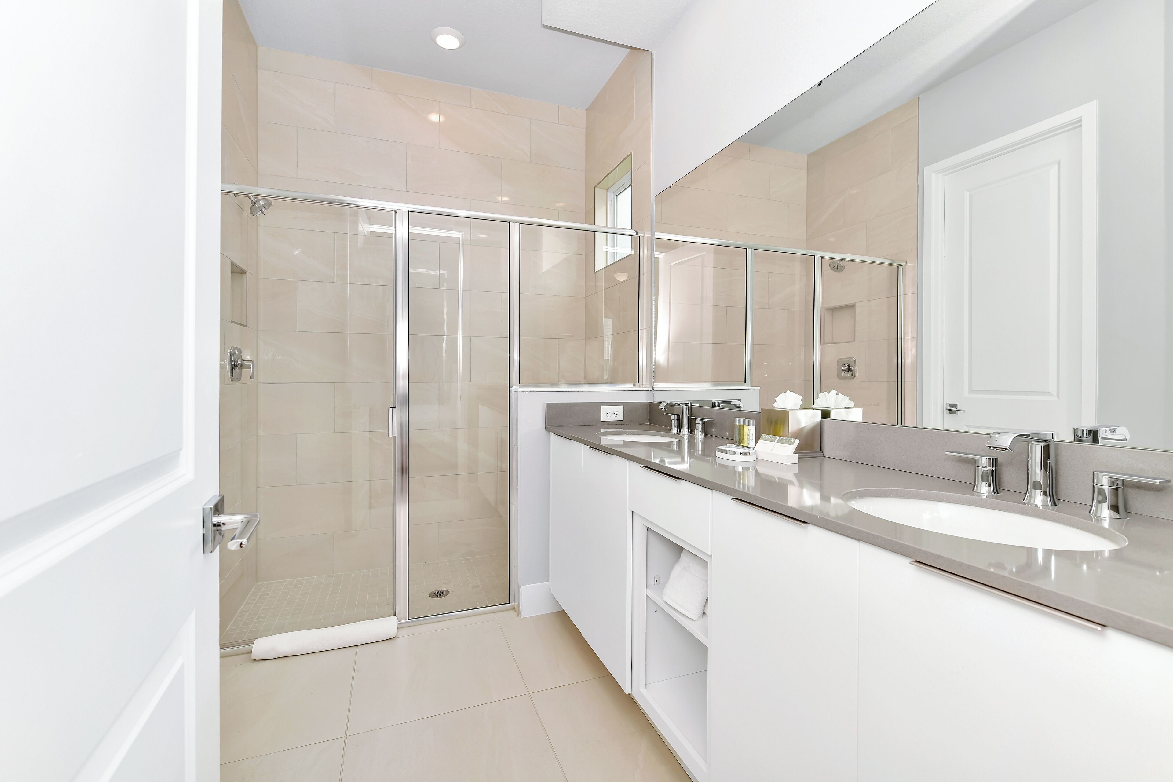 Un baño moderno con ducha envuelta en vidrio, un tocador espacioso con lavamanos y un espejo.