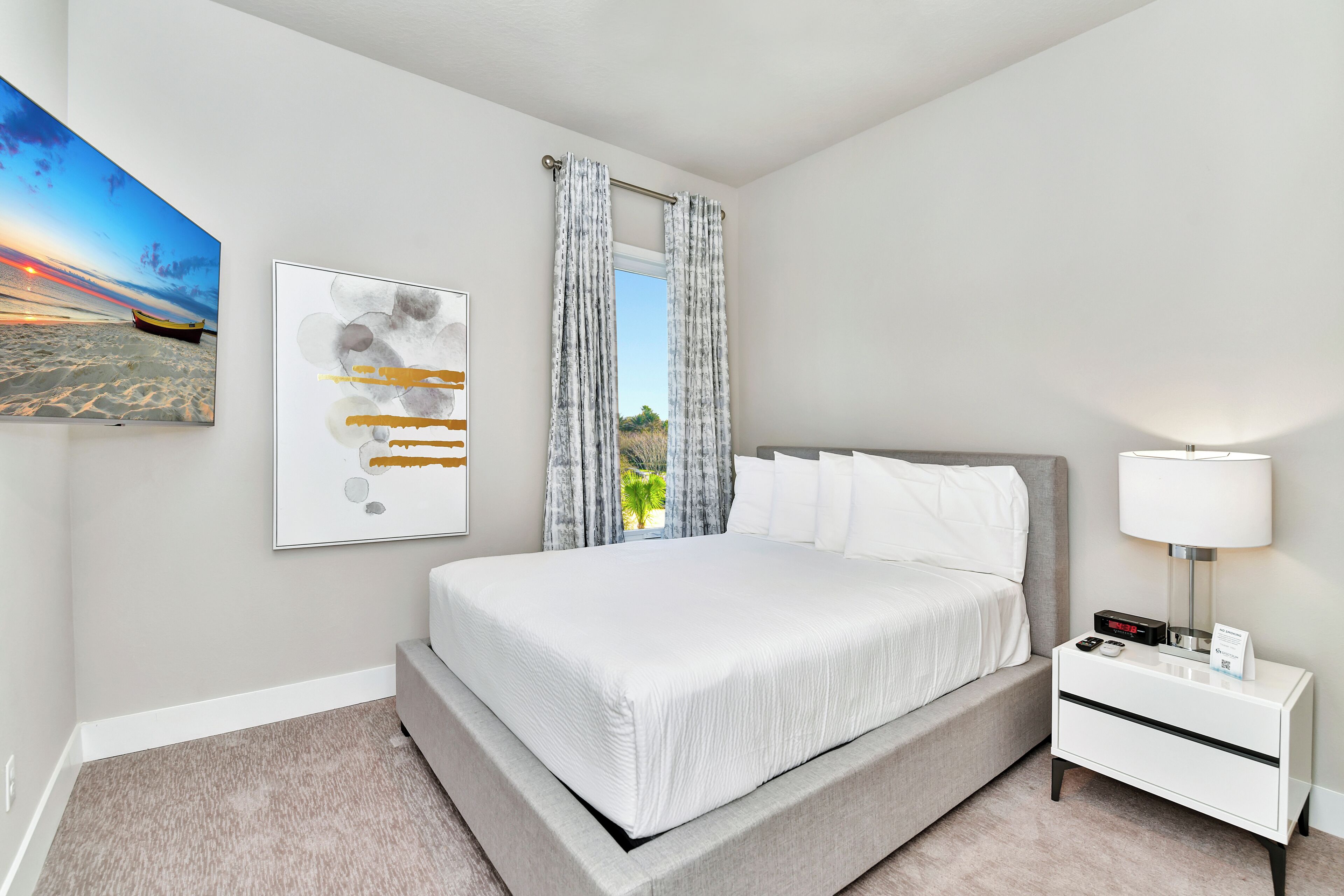 A bedroom with a bed, a nightstand, a lamp, and a window with curtains.