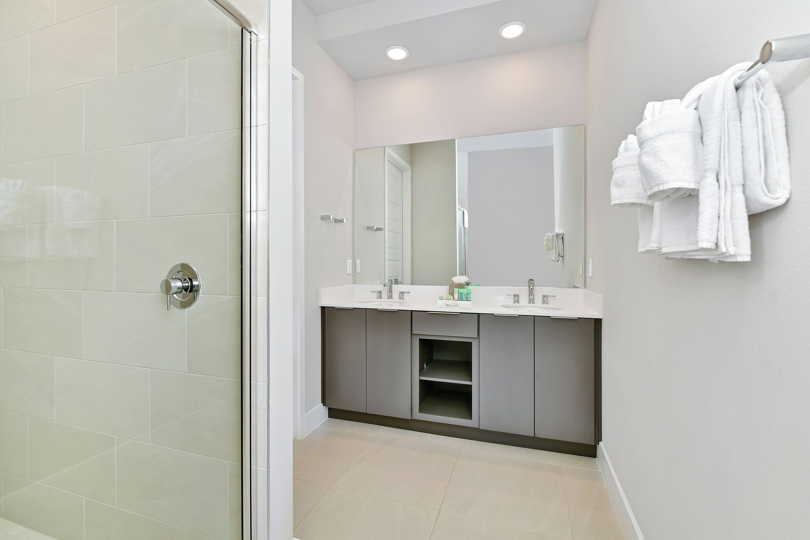 A modern bathroom with a glass shower door, a double sink vanity, and a towel rack.