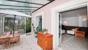 Un interior moderno con un patio envidriado, muebles de mimbre y un armario de madera.