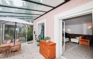 Ein modernes Interieur mit einem verglasten Patio, Korbmöbeln und einem Holzkabinett.