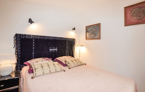 Une chambre à coucher avec un lit, deux lampes de chevet, une table de chevet et un tableau accroché au mur.