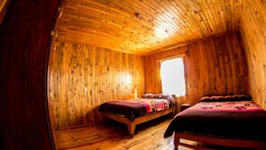 Una cabaña con dos camas de madera, una ventana y techo inclinado.