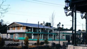 Un edificio con fachada verde y blanca, un balcón y una valla delantera.