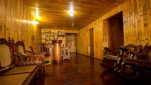 Una habitación con paneles de madera, un piso de madera pulida, una mesa grande de madera y varias sillas de madera ornamentadas.