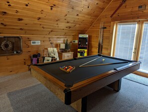 Relax in a spacious room with a pool table, comfortable seating area, and a decorative wreath on the wall.