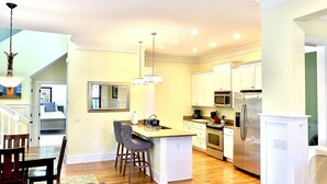 A modern kitchen with white cabinets, stainless steel appliances, and a central island with bar stools. - Beautiful Cottage on Hilton Head Island, Blue (Hilton Head Island)