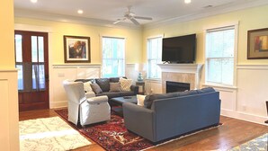 A living room with a sectional sofa, a fireplace, and a flat-screen TV. - Beautiful Cottage on Hilton Head Island, Blue (Hilton Head Island)