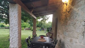 A covered patio with a table and chairs, stone walls, and a grassy yard with trees. - Rural house (pet-friendly) where you will only listen to nature. (Rianxo, A Coruña)