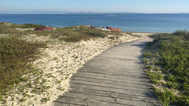 A sandy beach with a wooden boardwalk leading to the water, a red boat, and a small red structure. - Rural house (pet-friendly) where you will only listen to nature. (Rianxo, A Coruña)