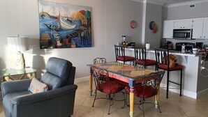 Een eethoek met een tafel en stoelen, een bank en een keuken op de achtergrond.