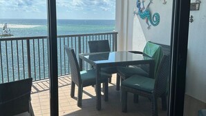 Een balkon met een tafel en stoelen, een plafondventilator en uitzicht op de oceaan.