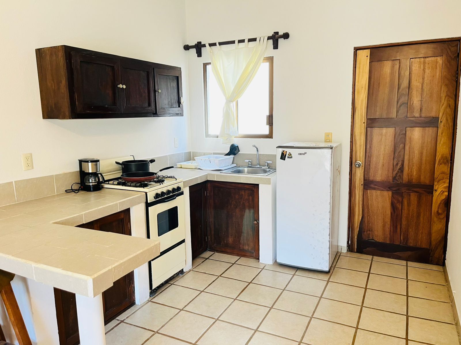 A compact kitchen with a stove, oven, sink, and a refrigerator.