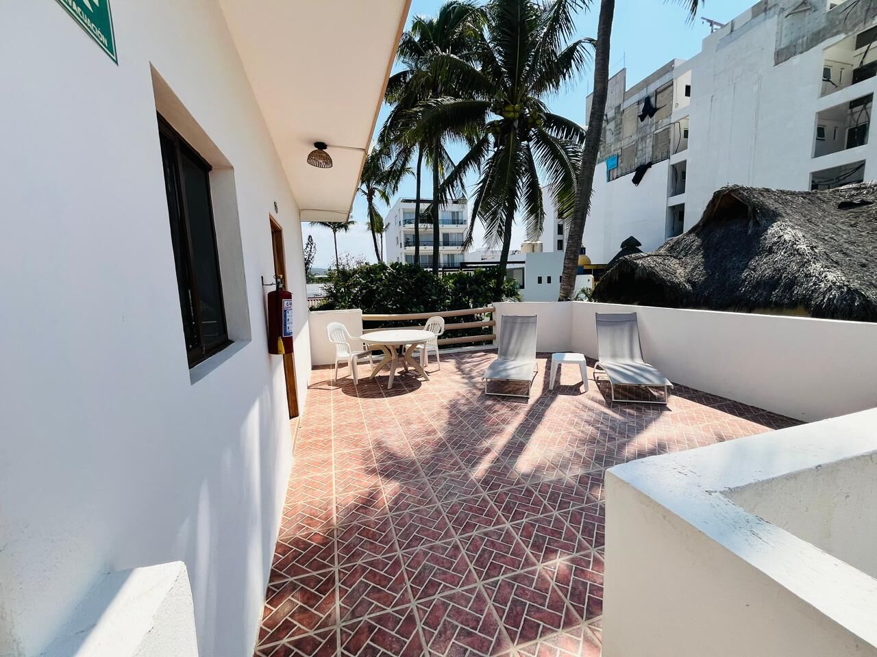 Eine Dachterrasse mit Fliesenboden, weißen Wänden und einer Dachkonstruktion aus Schilf.