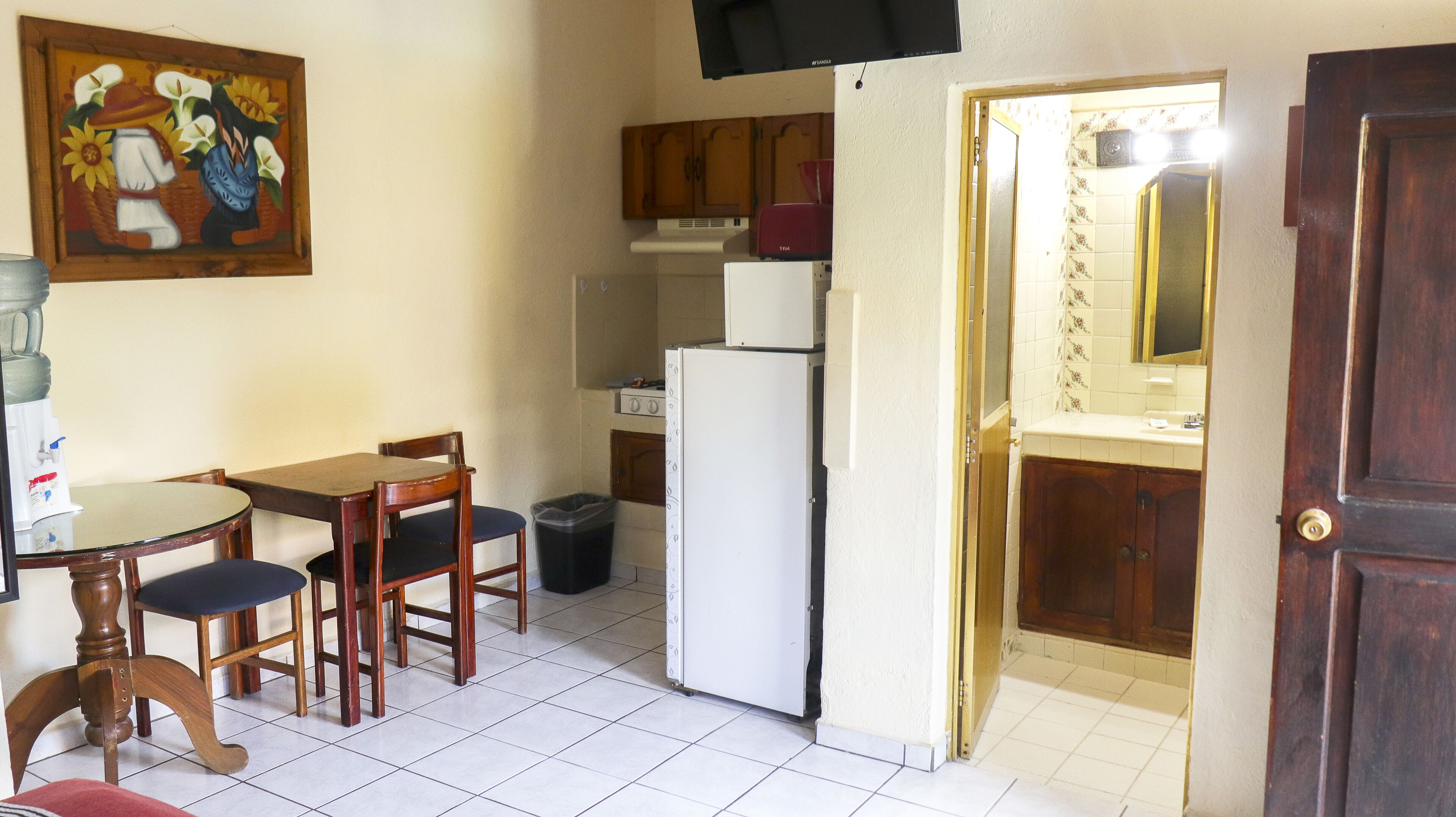 Una cocina compacta con una mesa de comedor, sillas, un refrigerador y armarios de madera.
