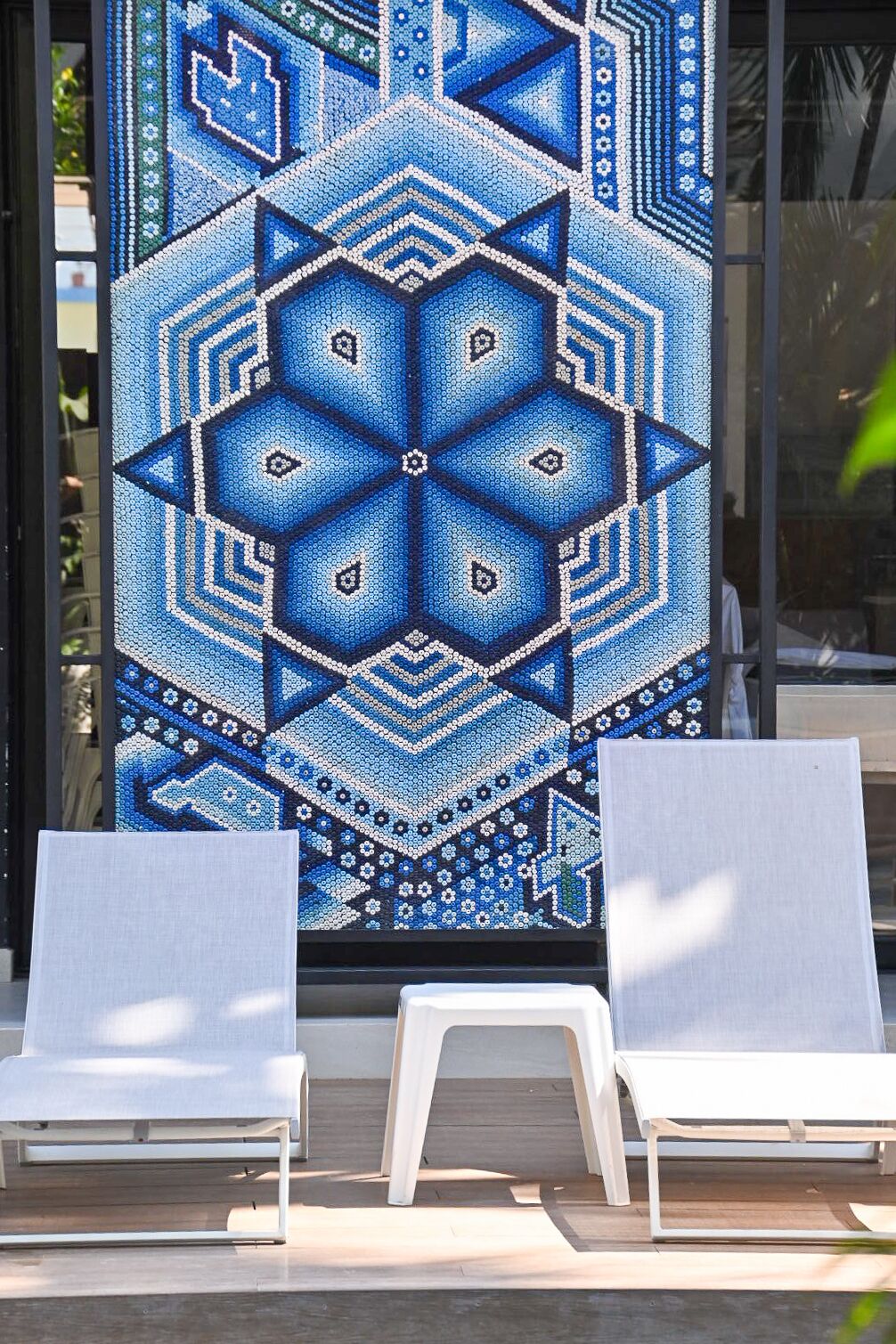 Pared con diseño geométrico, dos sillones blancos y una terraza de madera.