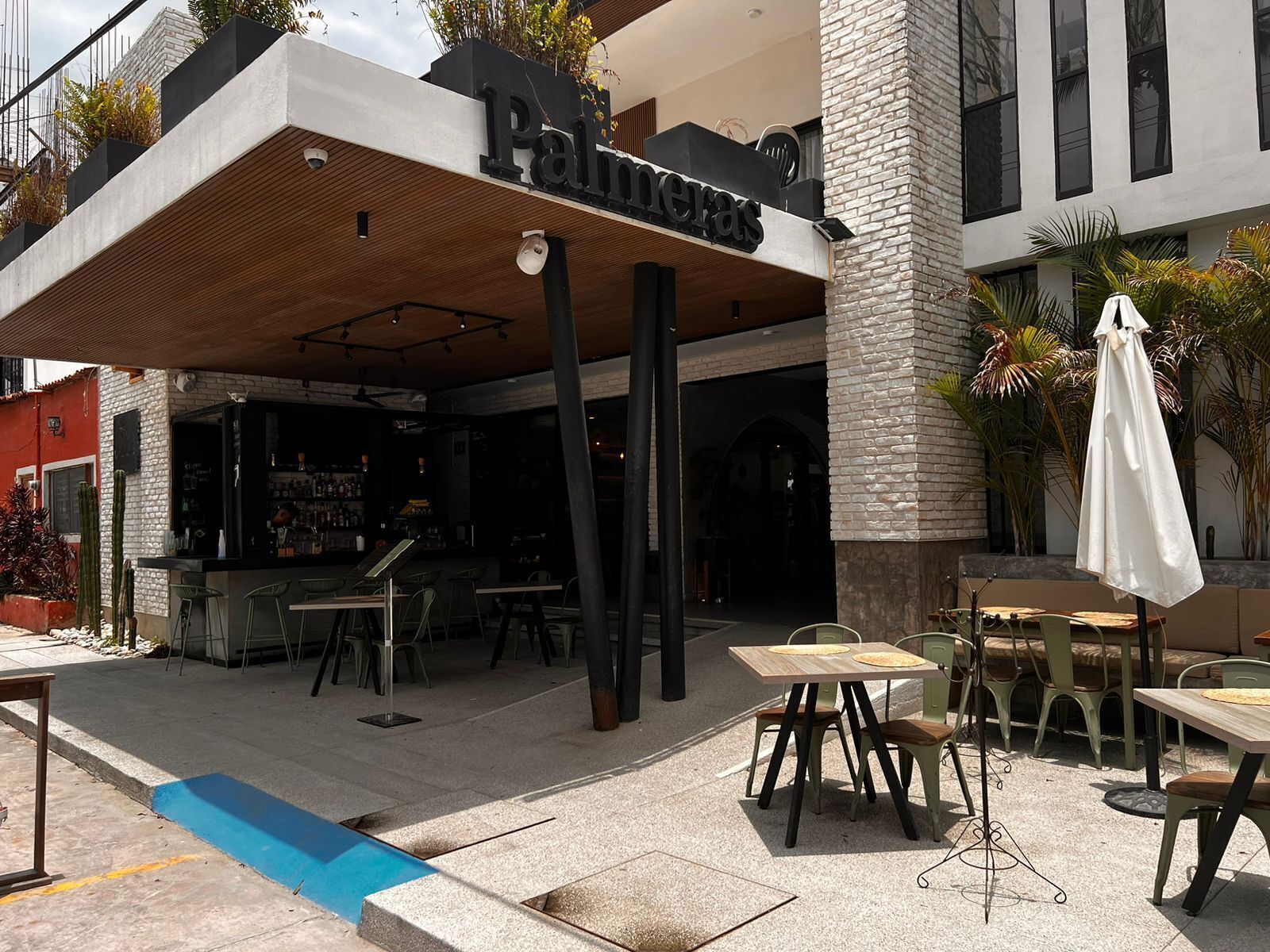 Un área de estar al aire libre con mesas, sillas, un bar y un letrero que dice 