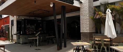 An outdoor seating area with tables and chairs, a bar, and a sign reading "Palmeras".