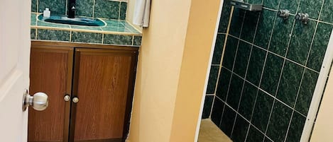Un bagno con doccia, lavabo con piano in marmo e mobili in legno.