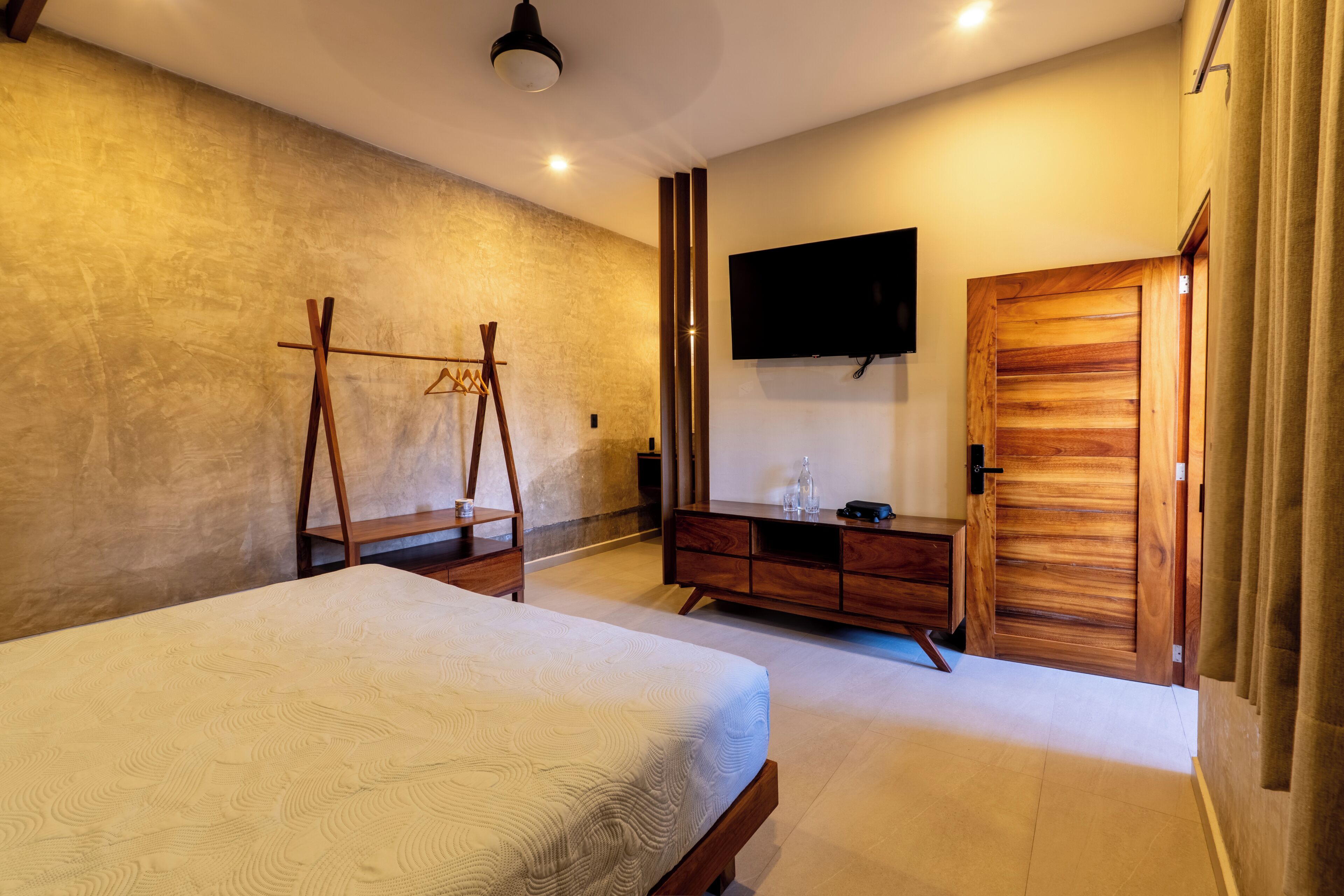 Un dormitorio con cama, cómoda de madera, televisor y armario.