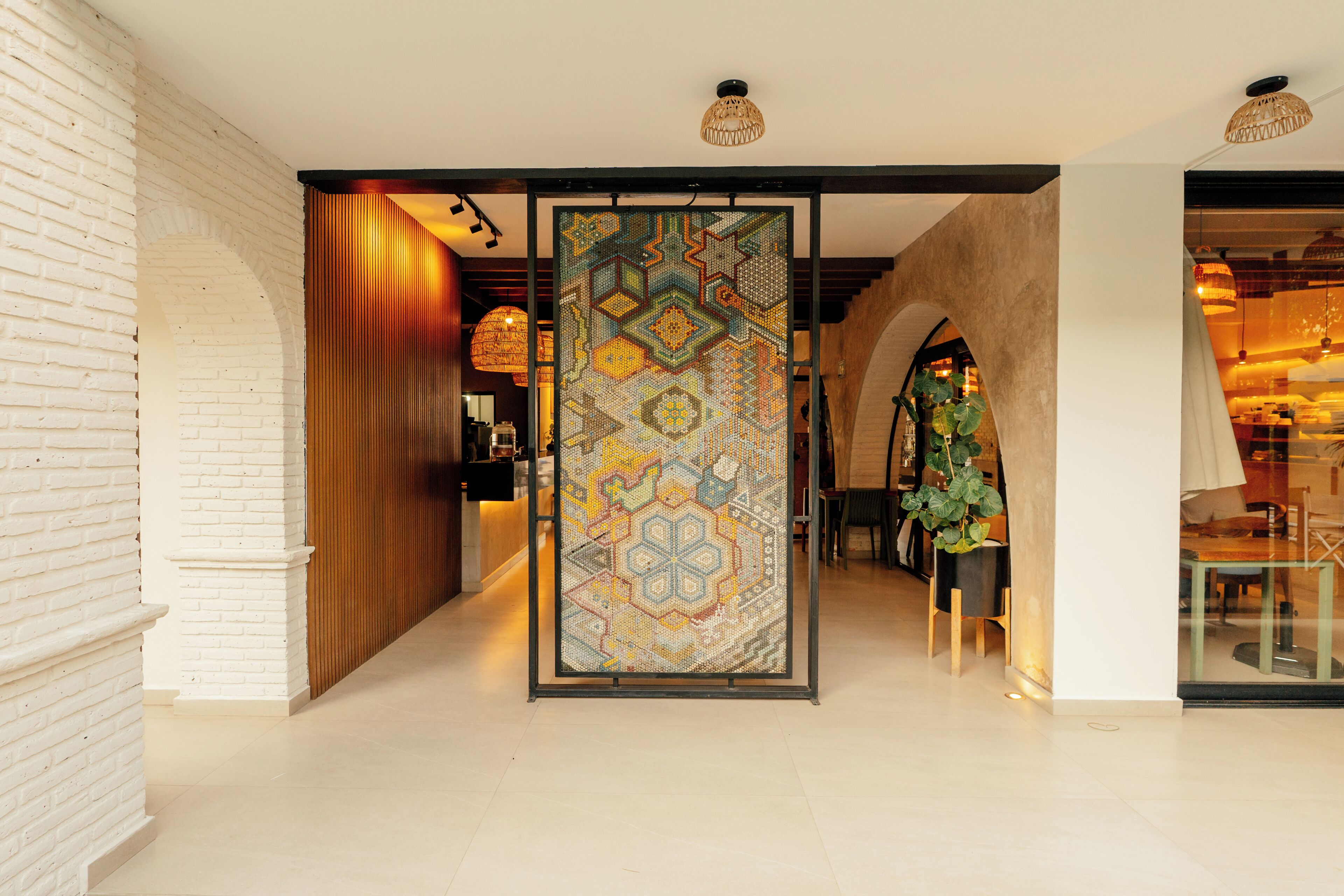 A corridor with a patterned partition, white brick walls, and a wooden reception desk.