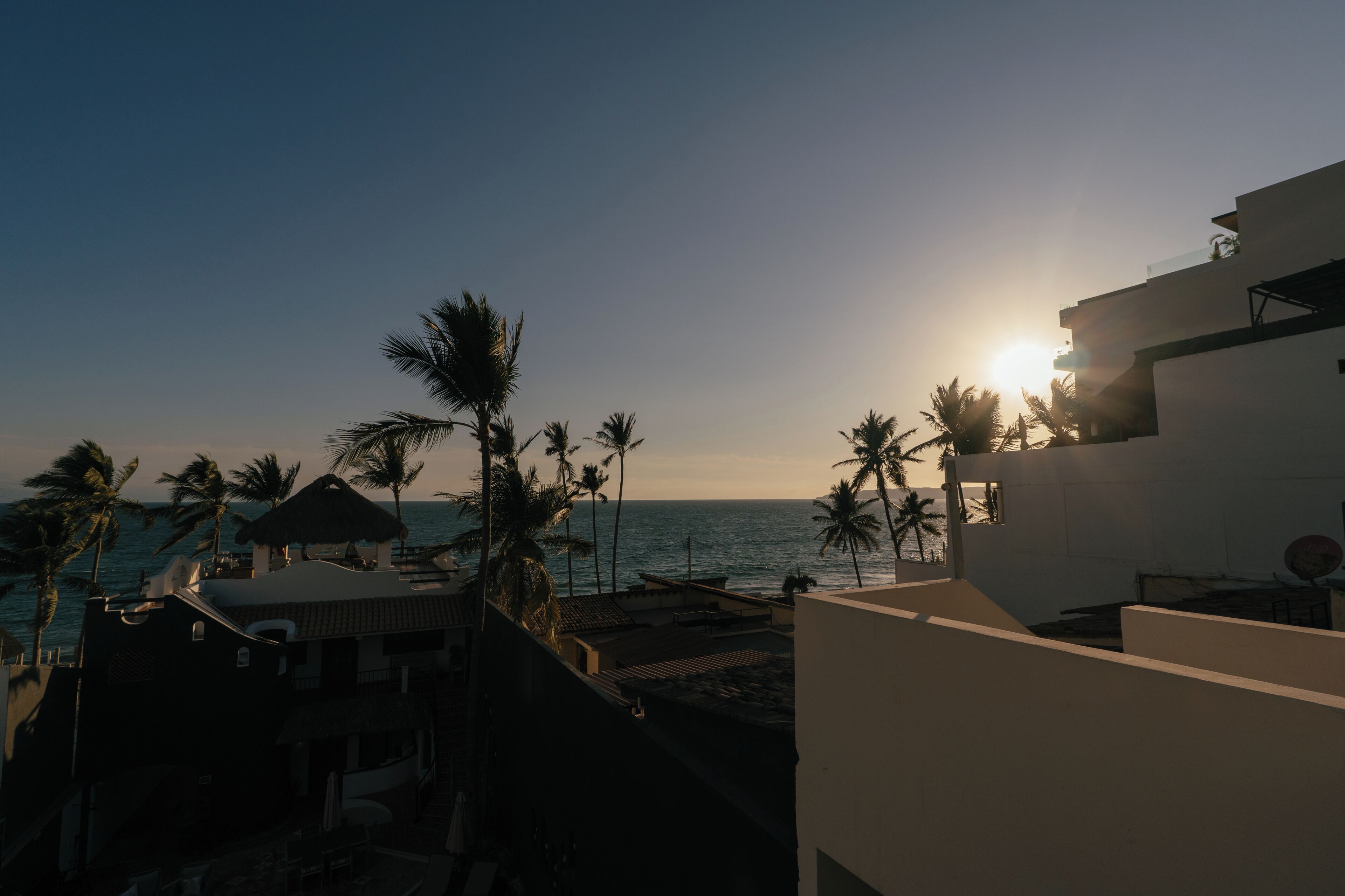 A resort with a beach view, palm trees, and a building with a flat roof.