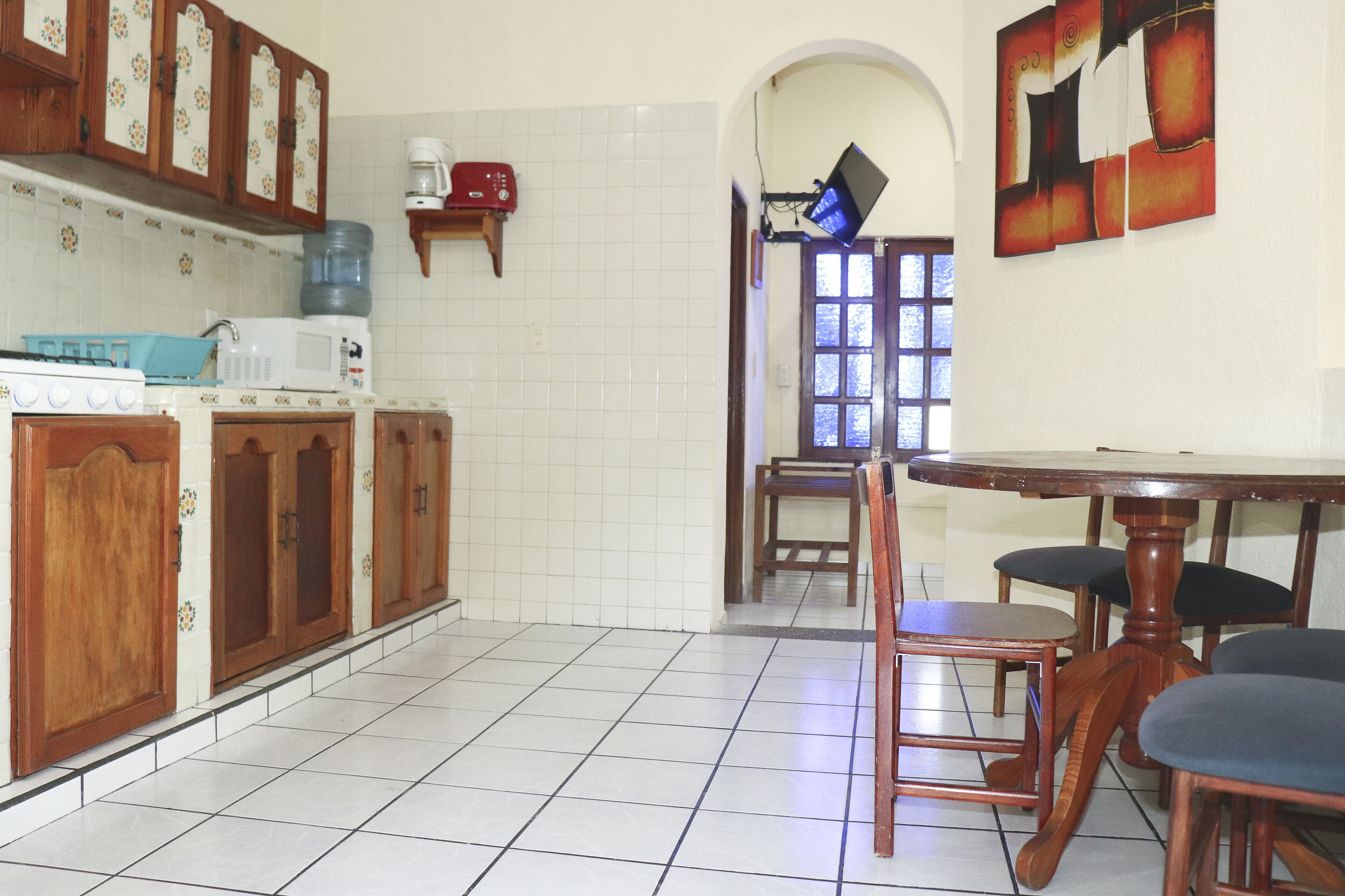 Une cuisine avec des meubles de rangement en bois, une cuisinière et un four à micro-ondes. On y trouve également une table à manger avec des chaises.