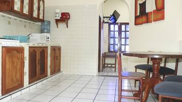 Una cocina con armarios de madera, una estufa y un microondas. Hay una mesa de comedor con sillas.