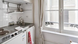 A kitchen with white cabinets, a stainless steel stove, and a window with a view of buildings.