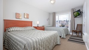 A hotel room with two beds, a TV mounted on the wall, and a chair. - Paradise Canyon Golf Resort - Luxury Condo M403 (Lethbridge)