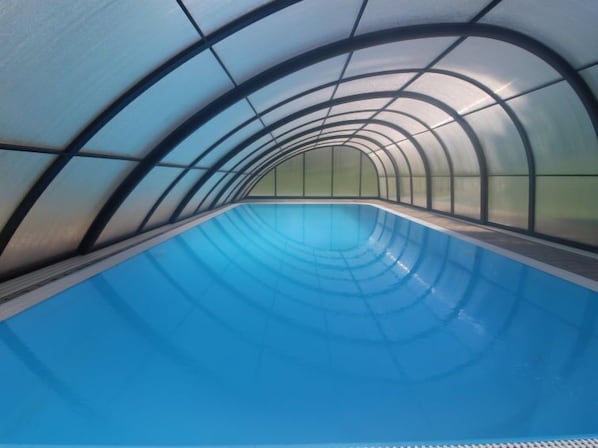 A swimming pool with a curved ceiling and glass panels.