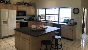 A kitchen with wooden cabinets, a refrigerator, a microwave, a sink, and a window with a view. - Cozy Oasis (Port St. Lucie)