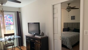 A bedroom with a bed, a TV on a cabinet, a ceiling fan, and a door leading to another room. - Cozy and fresh one-bedroom, 10 minutes from Old Town Alexandria (Alexandria)
