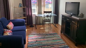 A living room with a blue sofa, a small table, a TV, and a patterned rug. - Cozy and fresh one-bedroom, 10 minutes from Old Town Alexandria (Alexandria)