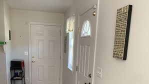 A hallway with a wooden floor, a white door, and a small table with a red cushion. - Cozy and fresh one-bedroom, 10 minutes from Old Town Alexandria (Alexandria)