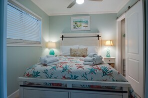 A bedroom with a bed, two bedside lamps, a ceiling fan, and a painting on the wall. - Ocean view - Beautiful Penthouse Condo - Large heated pools & Hot Tubs! (Hilton Head Island)