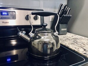 Kitchen area with a Whirlpool stove, digital clock, and utensil holder.