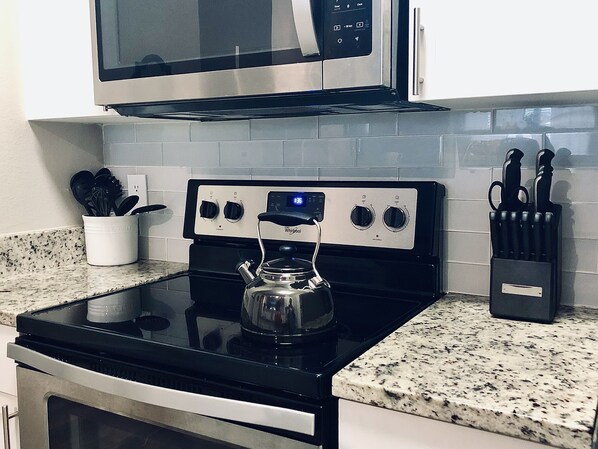 Kitchen area with a stove, microwave, and granite countertop.