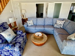 A living room with a blue patterned sofa, a round wooden coffee table, and a blue patterned armchair.