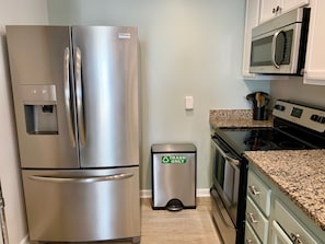 A stainless steel refrigerator, a trash bin, a microwave, and a stove in a kitchen. - Upscale Oceanfront, with Panoramic Views (Emerald Isle)