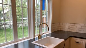 Une cuisine avec un évier blanc, un plan de travail noir et des placards blancs.