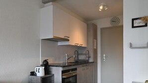 Eine kleine Küche mit Backofen, Kaffeemaschine und einer Arbeitsplatte.