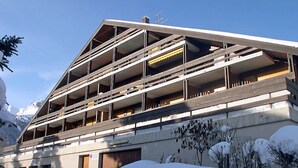 Ein mehrstöckiges Gebäude mit einem geneigten Dach, Balkonen und einer Garage.