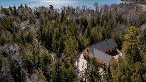 A cabin surrounded by dense forest with a view of a large body of water.